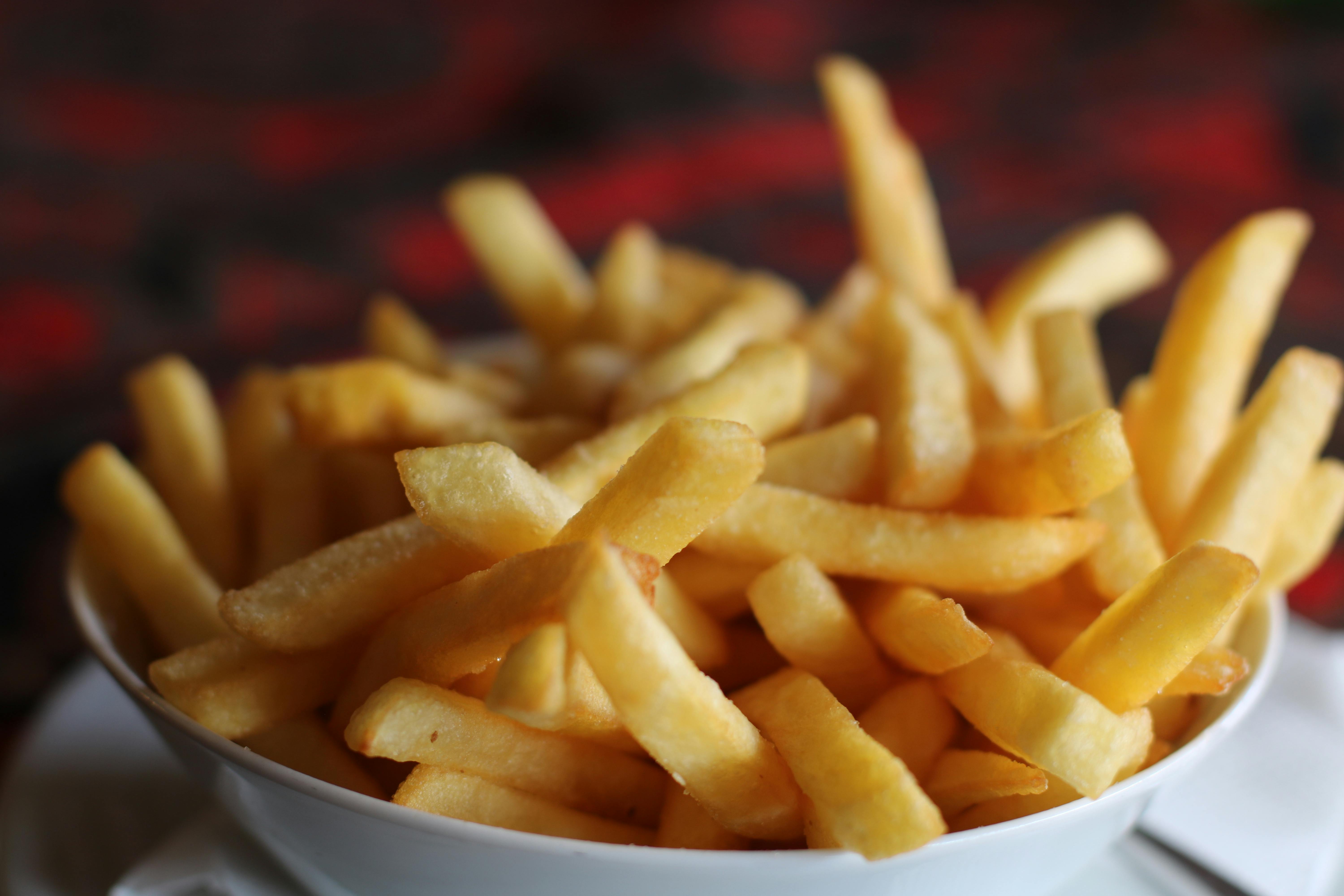 Delicious crispy golden french fries served in a white bowl, perfect for a tasty snack.