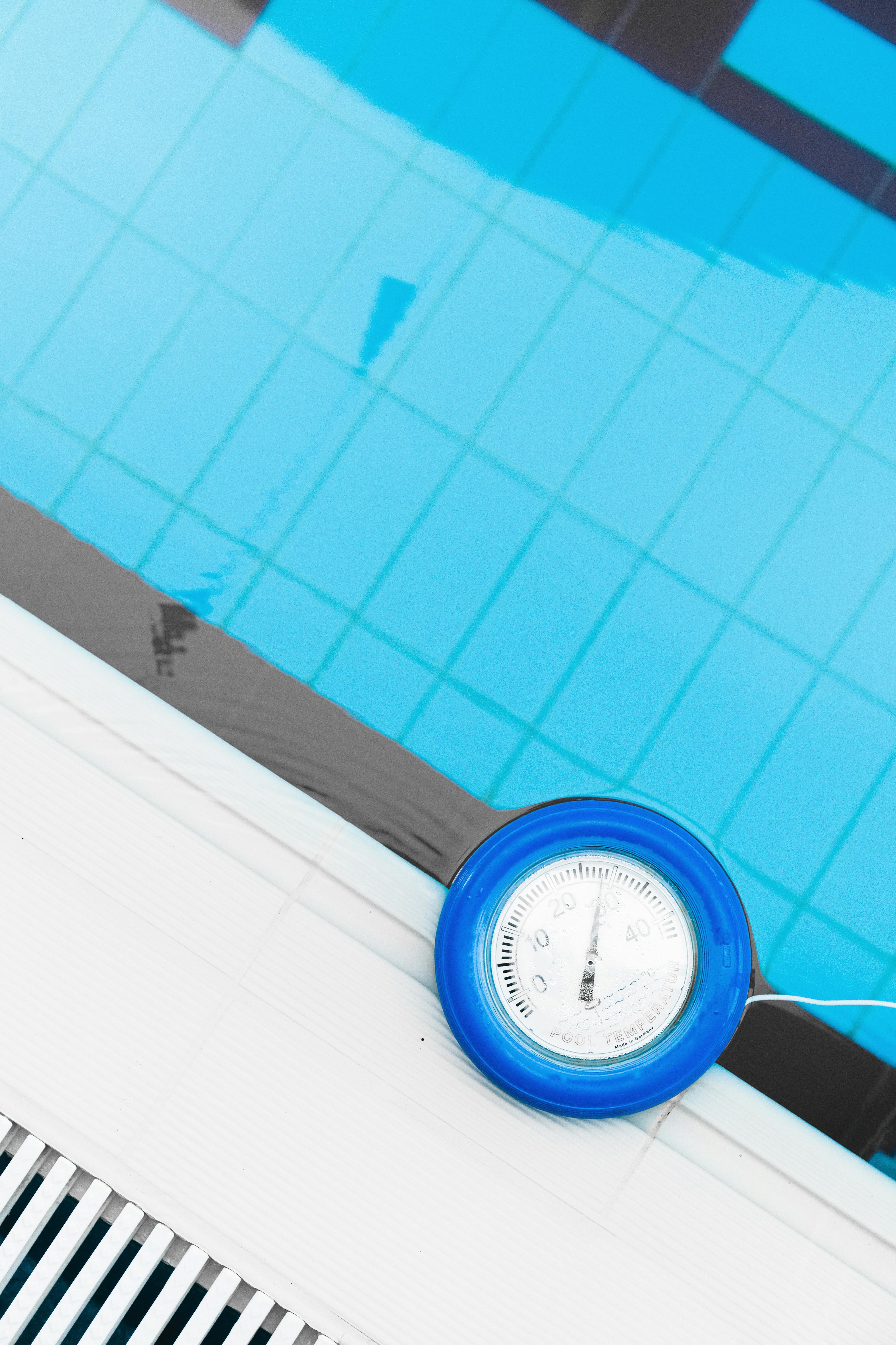 A clear swimming pool with a thermometer measuring water temperature. Top view shot.