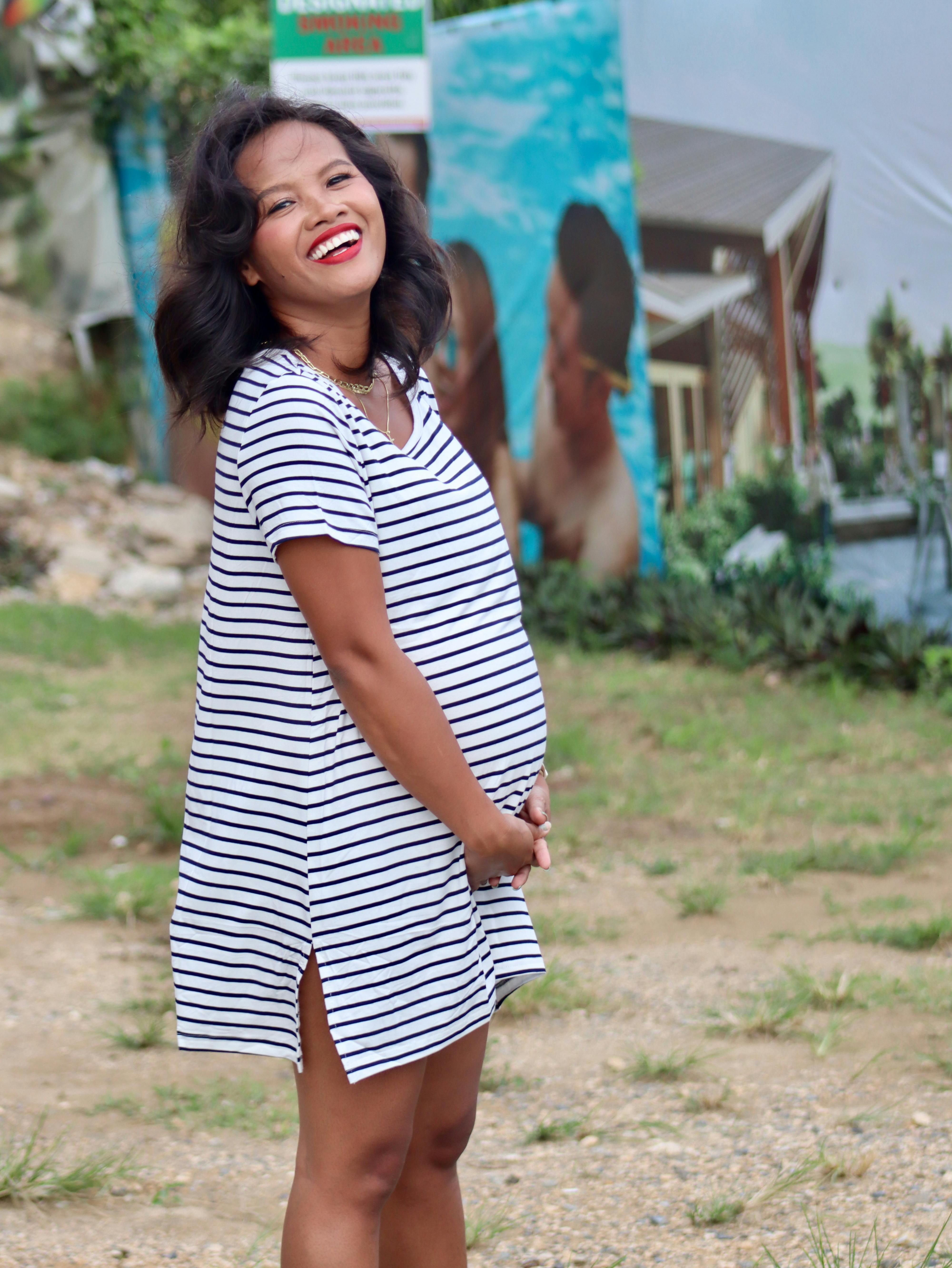 A joyful pregnant woman enjoying the outdoors with a vibrant smile.