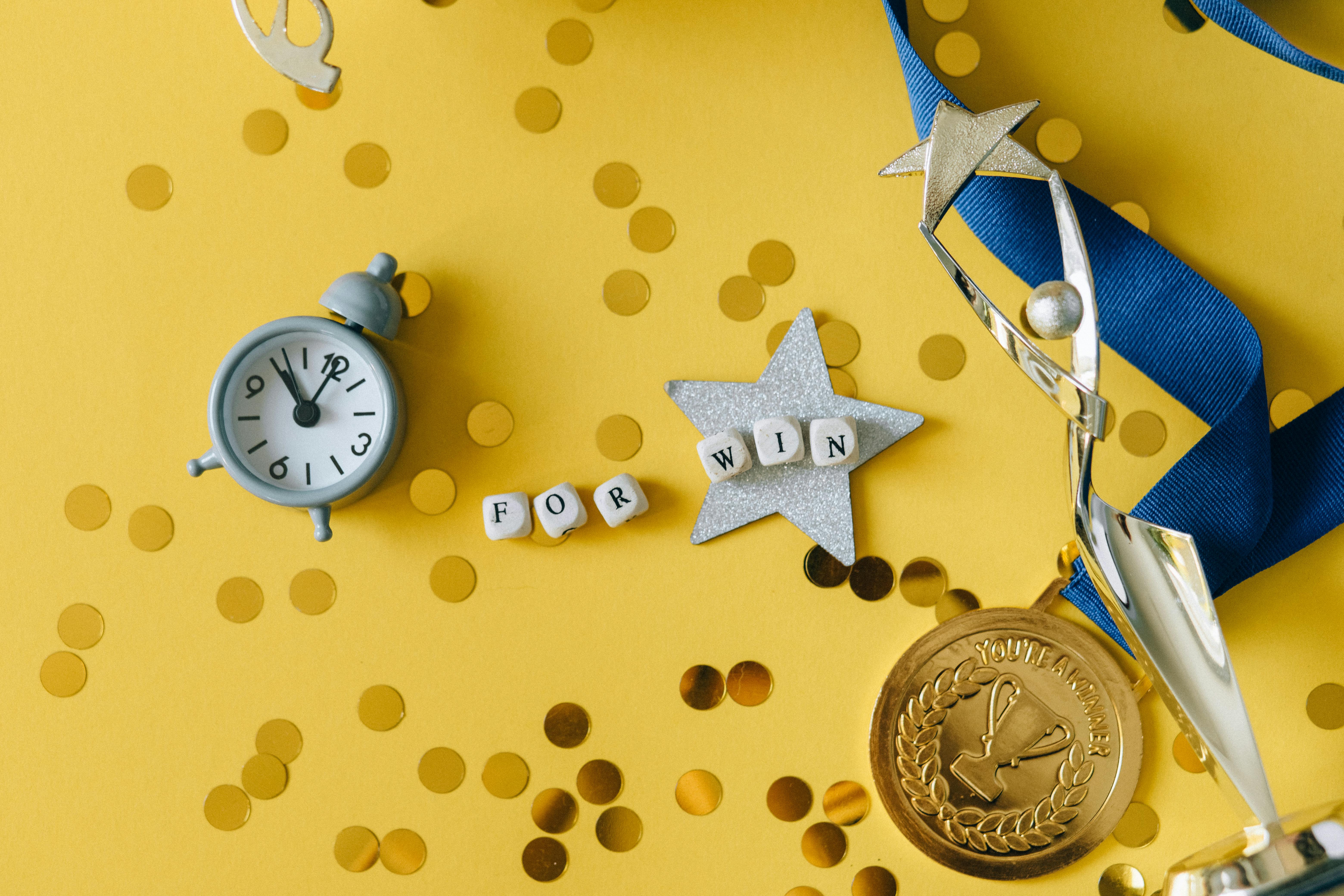 Conceptual flat lay of a trophy, medal, and clock with 'FOR WIN' letters, symbolizing victory and achievement.