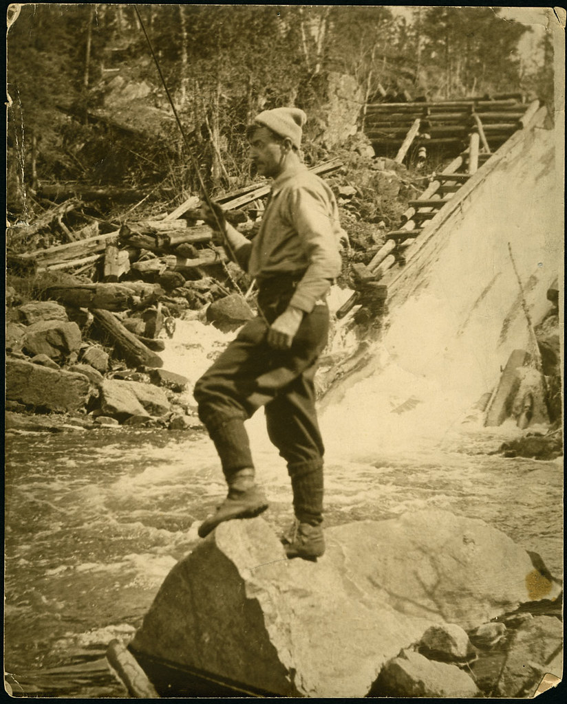 Tom Thomson, standing on a rock and fishing in moving water / Tom Thomson, debout sur une roche pour pêcher dans les eaux vives