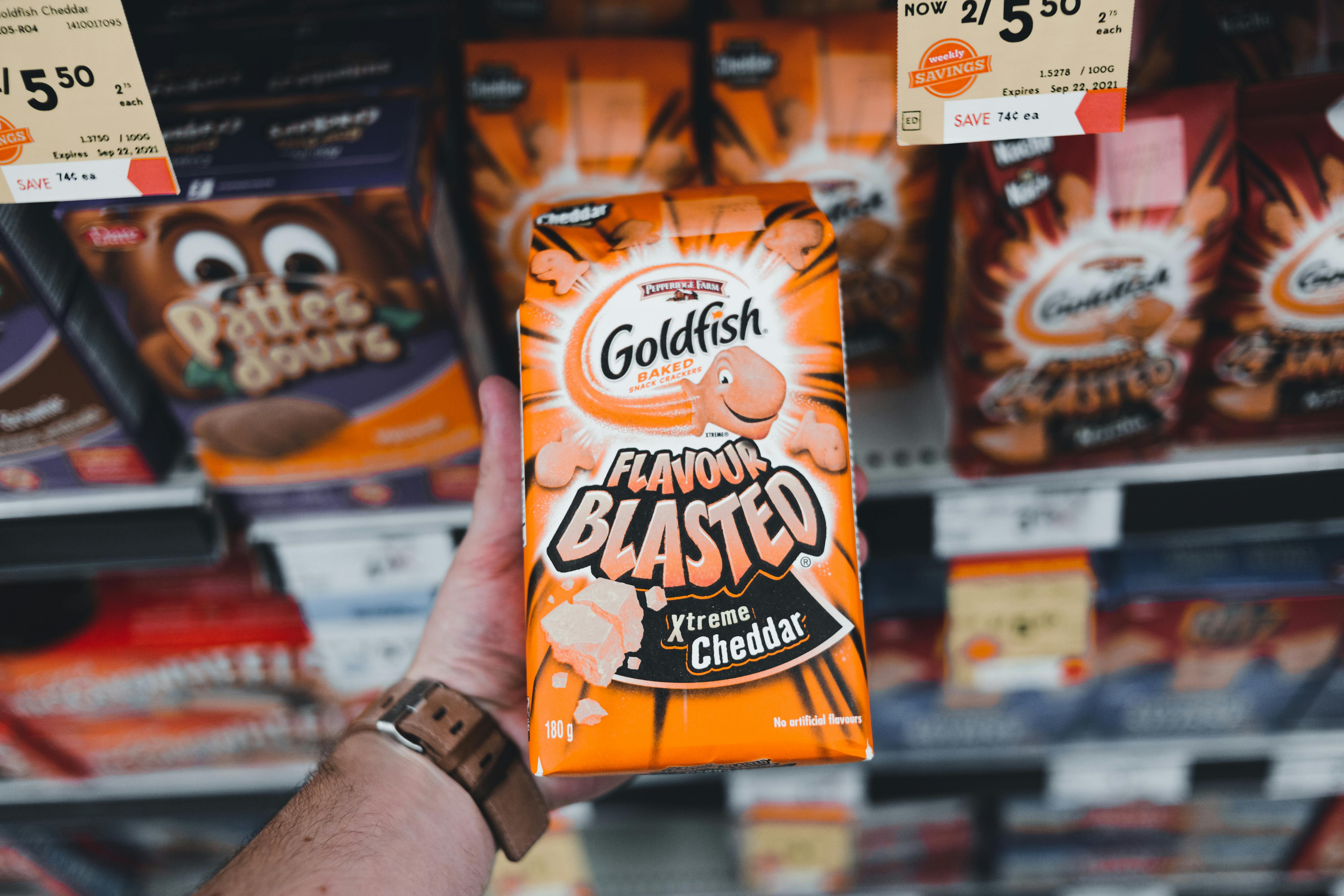Close-up of hand holding Goldfish Flavour Blasted Xtreme Cheddar snack in a grocery store.